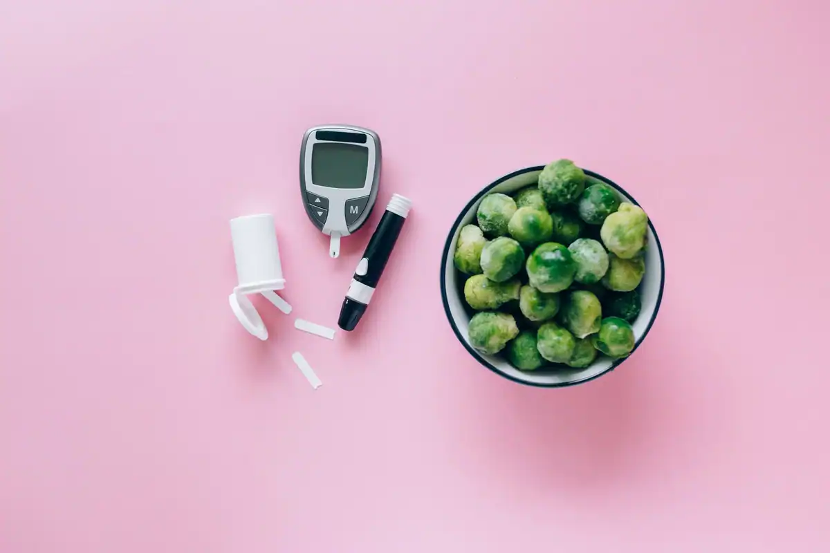 Glucometru lângă o strachină cu varză de Bruxelles, legume cu indice glicemic mic