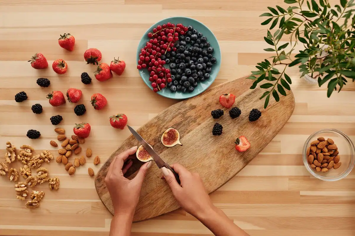 Mâini care taie fructe și nuci pe un tocător, ingrediente simple și ușor de recunoscut
