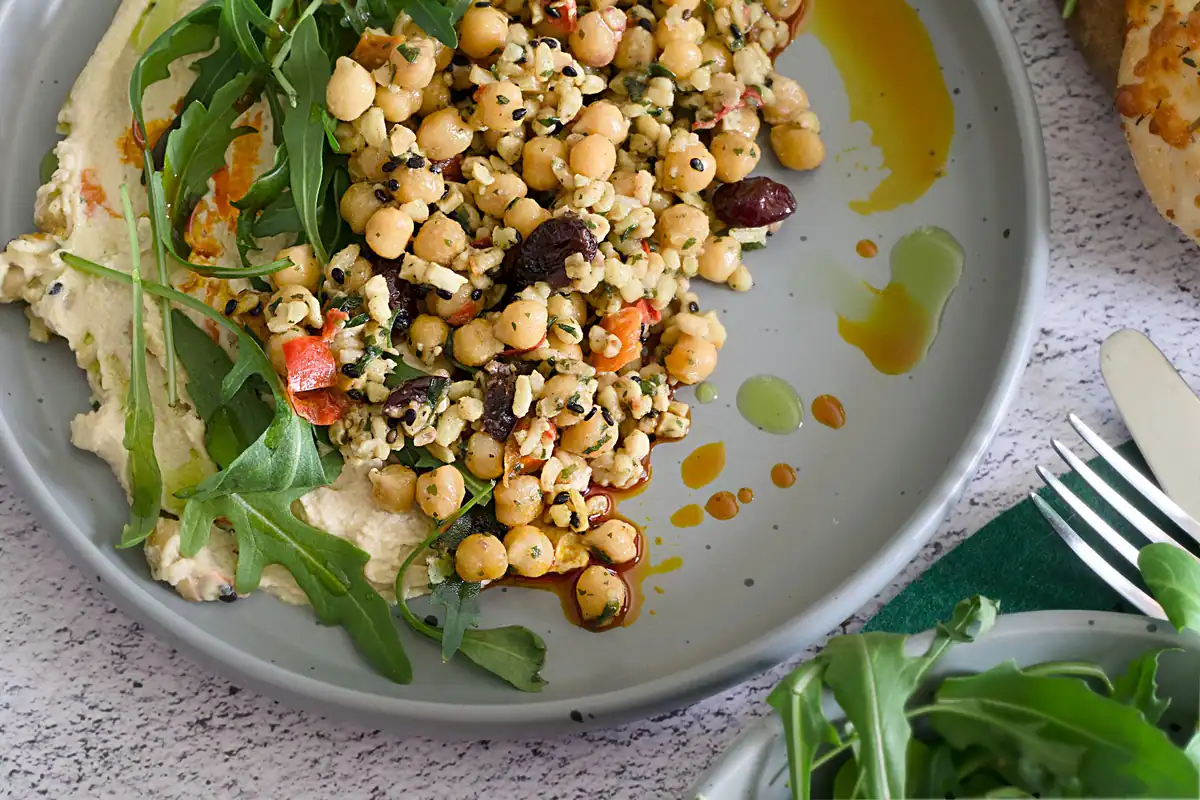 Salată mediteraneană cu năut, humus și rucola stropită cu ulei de măsline