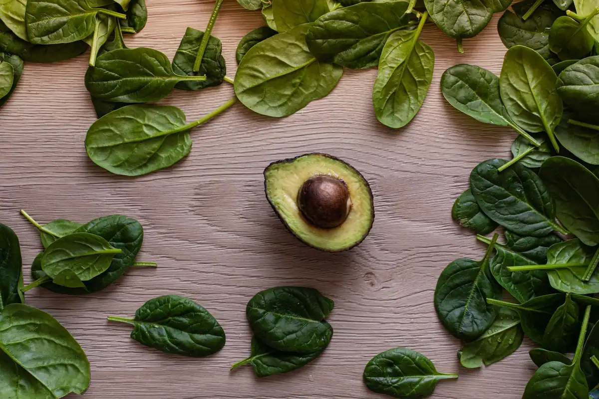 Avocado și frunze de spanac pe o masă de lemn, alimente bogate în minerale