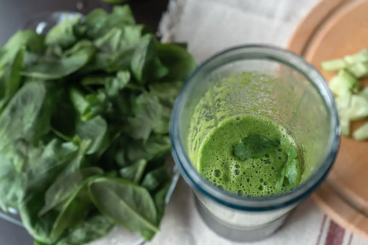 Smoothie verde din spanac și castraveți pe un tocător, băutură prezentată drept detox