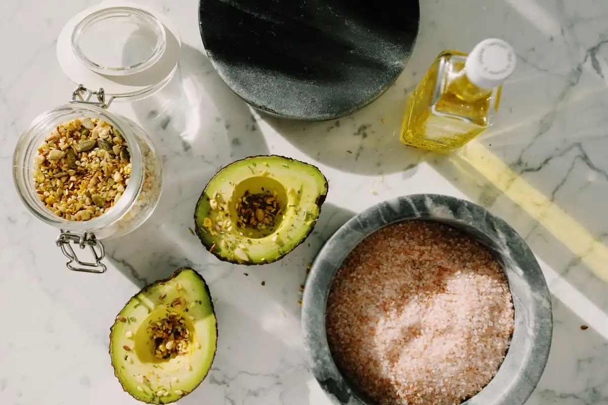 Avocado tăiat în jumătăți, cu semințe și sare roz, surse de grăsimi sănătoase