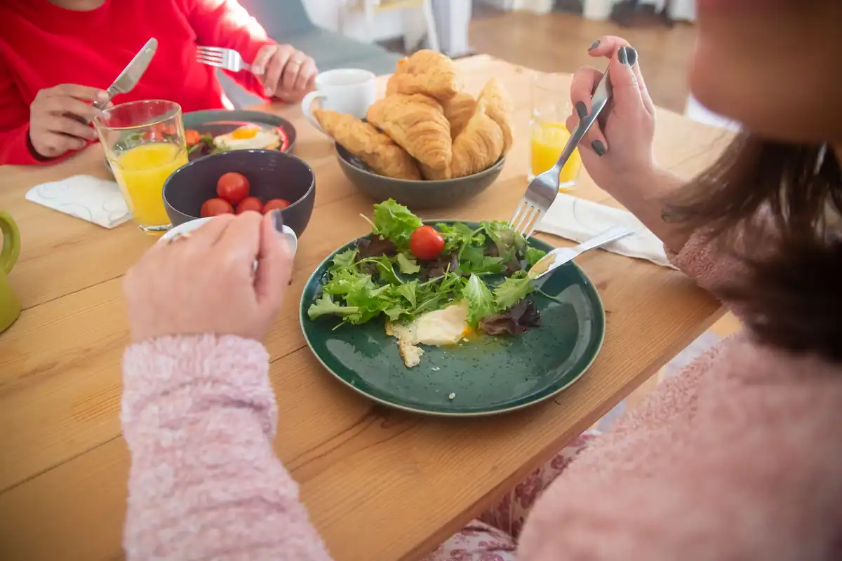 Familie la masă cu salată, croissante și suc, discuții despre mituri alimentare