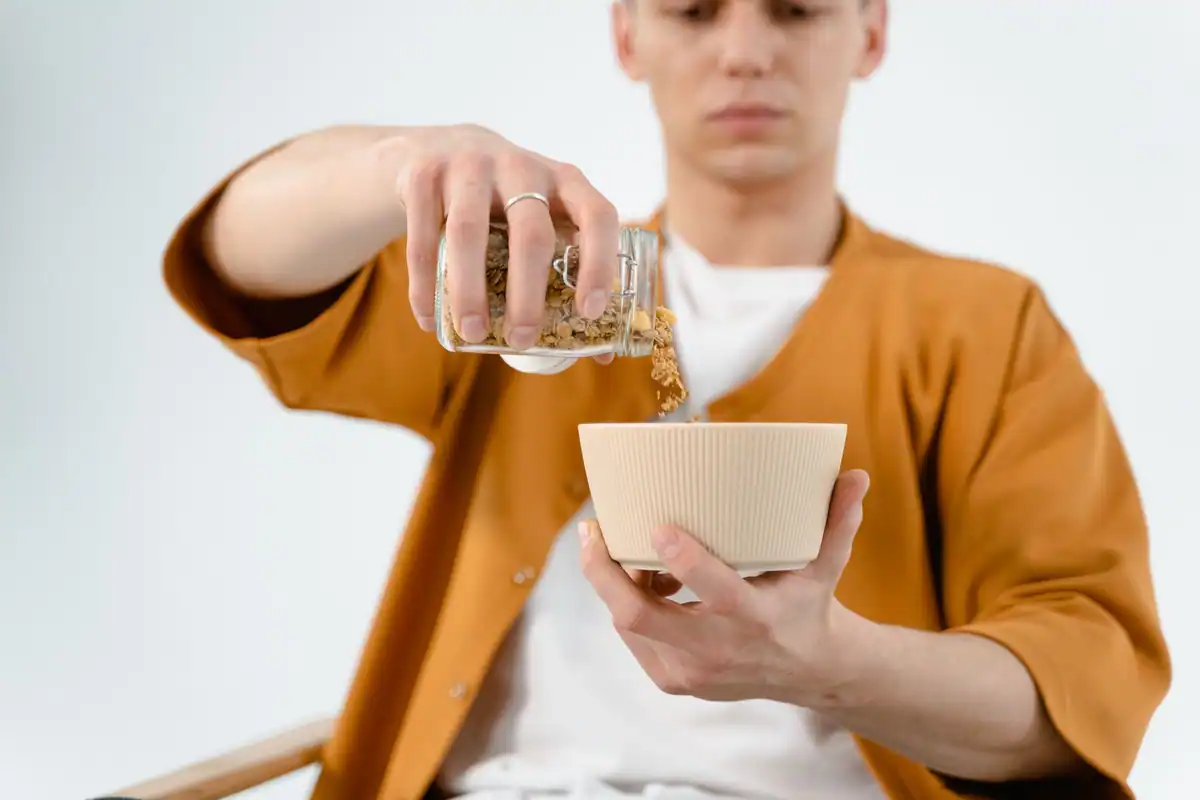 Bărbat care toarnă cereale dintr-un borcan într-un bol, măsurând o porție